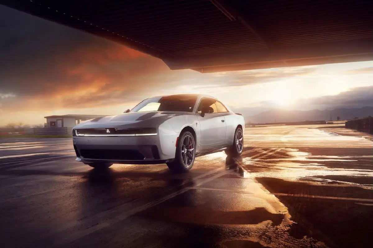Silver Dodge Charger Daytona electric muscle car parked under an airport hangar at sunset