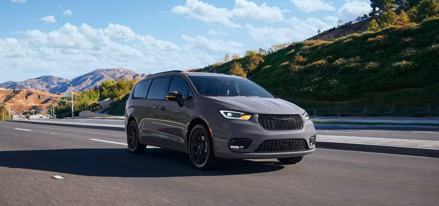 2024 Gray Chrysler Pacifica minivan driving on a highway with mountain scenery in the background