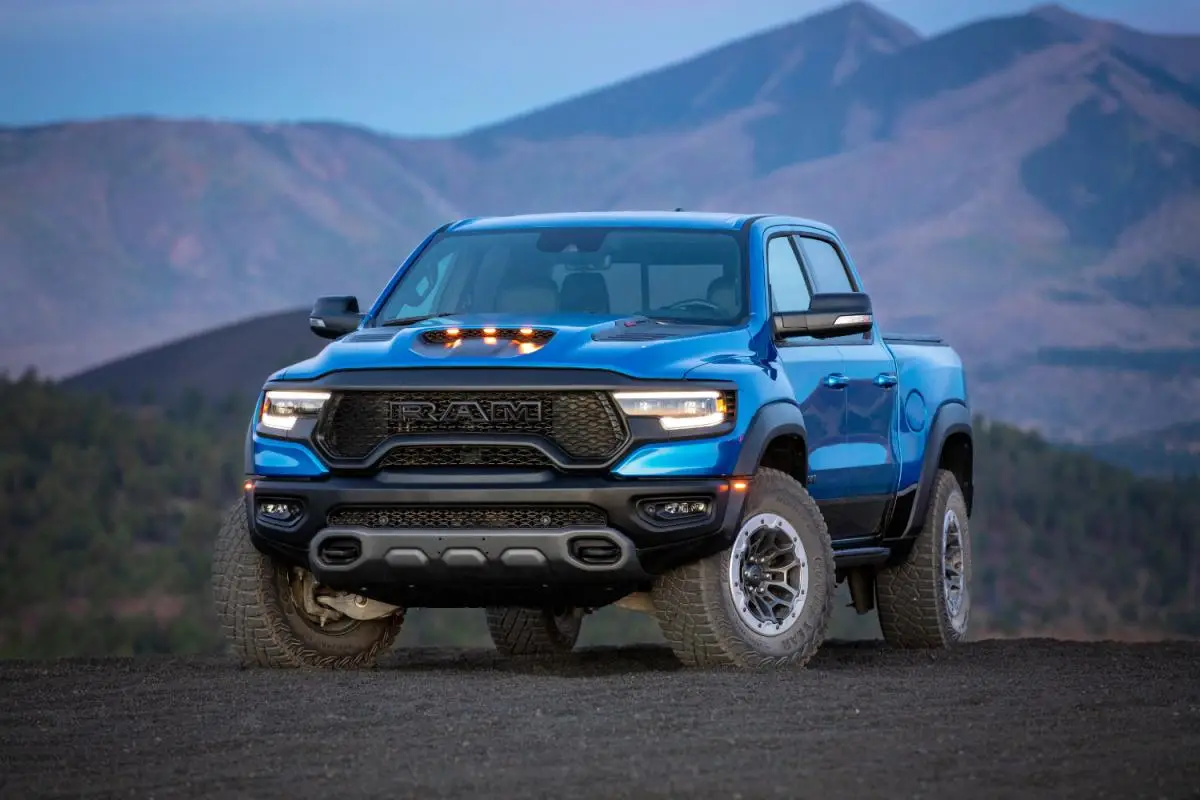 2024 Blue Ram 1500 TRX off-road pickup truck parked on a dirt hilltop at dusk with mountain views