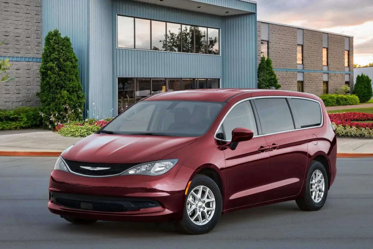2025 Dark red Chrysler Pacifica minivan parked outside a modern office building at dusk