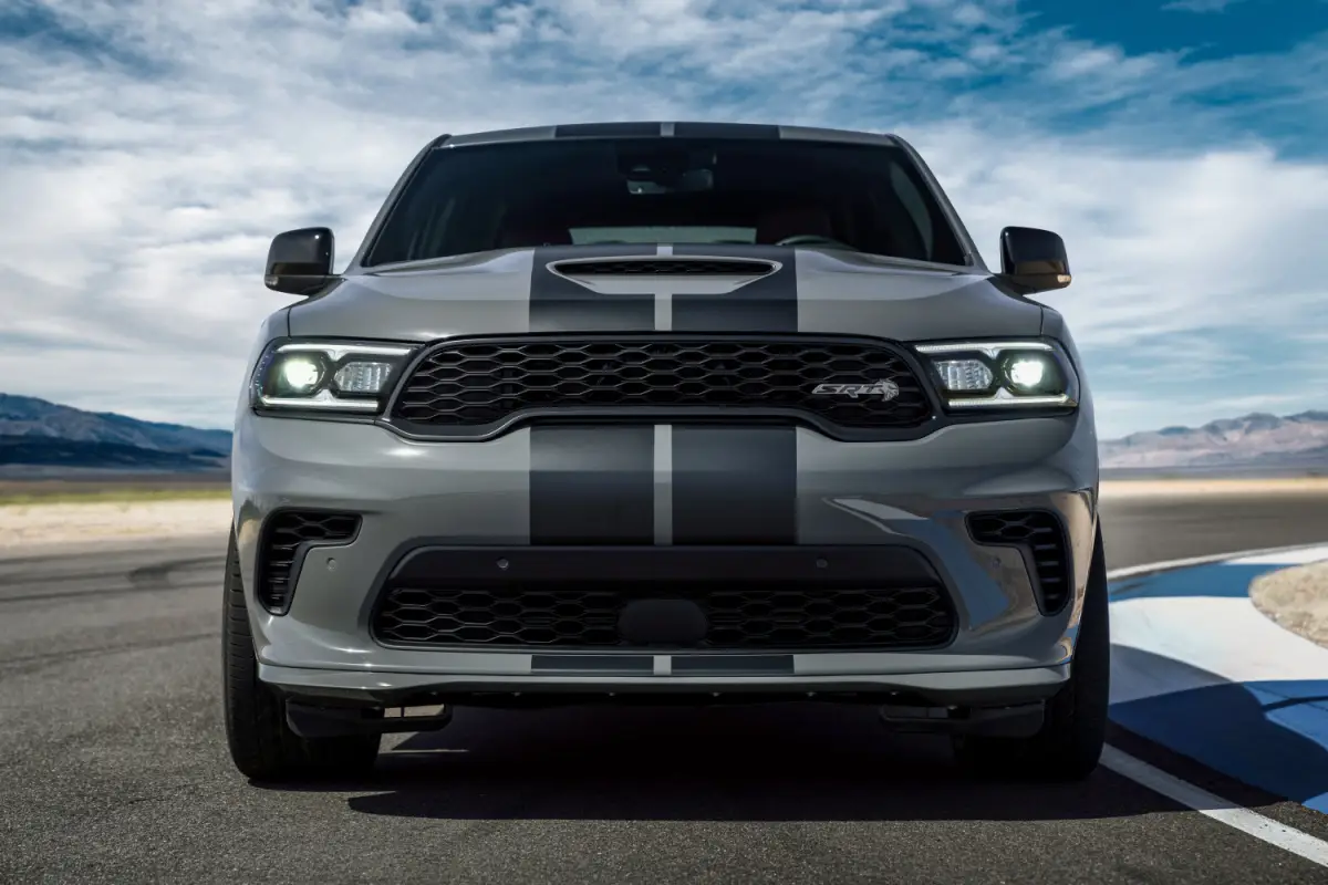 The 2024 Gray Dodge Durango SRT SUV with black racing stripes parked on a racetrack, front straight-on view