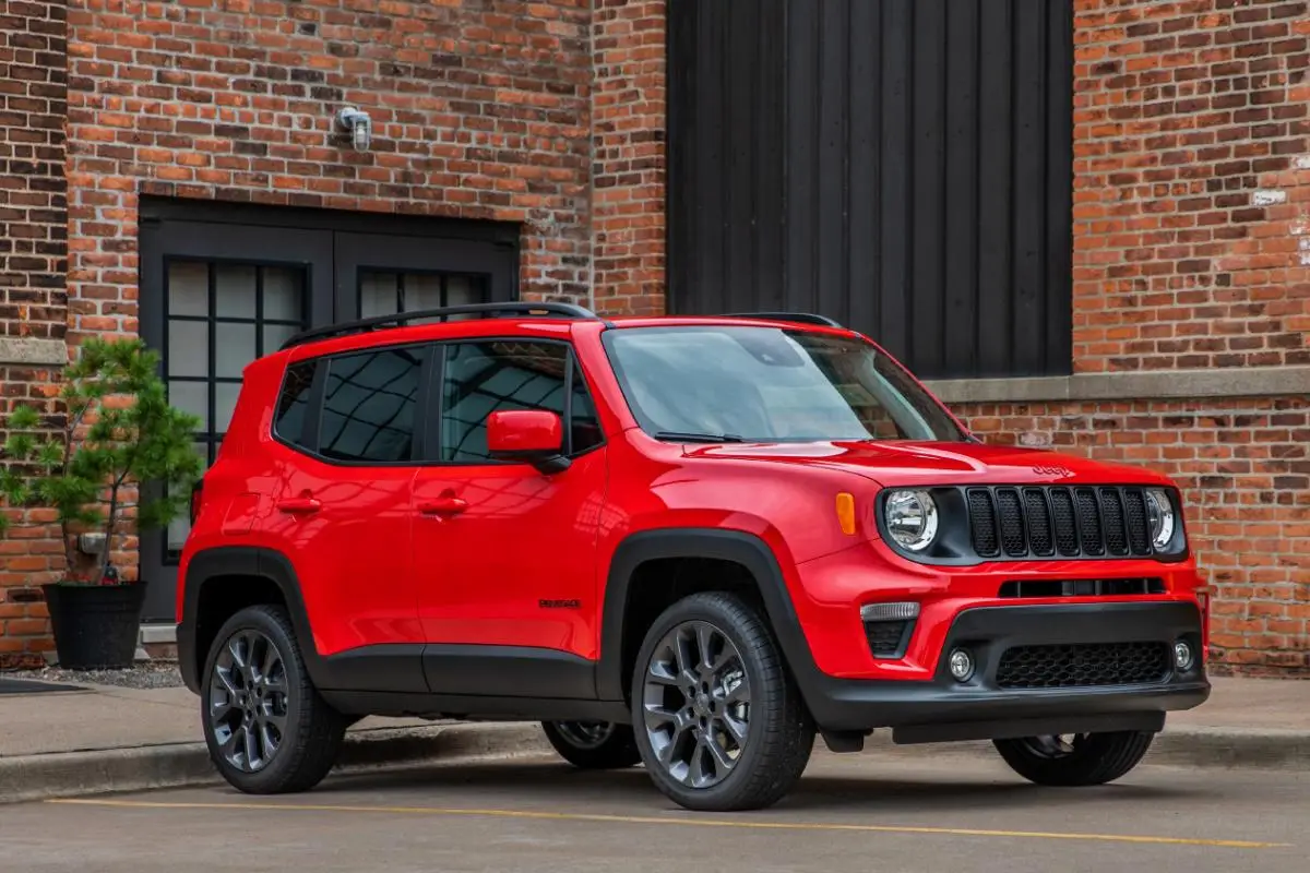 Red Jeep Renegade compact SUV parked in front of a brick building, front three-quarter view