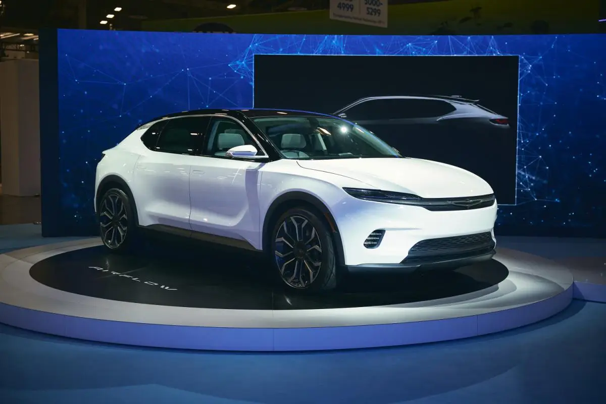 White Chrysler Airflow electric concept SUV displayed on a rotating stage at an auto show