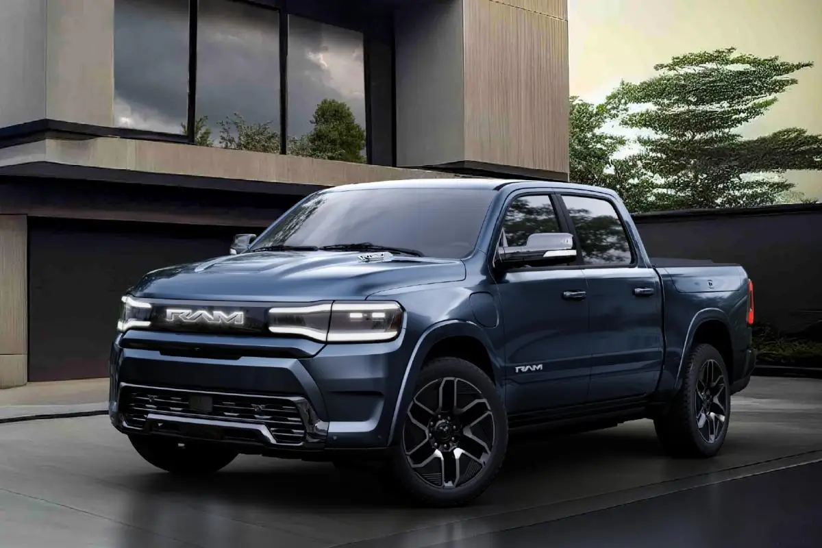 2025 Dark blue Ram 1500 REV electric pickup truck parked outside a modern home, front three-quarter view