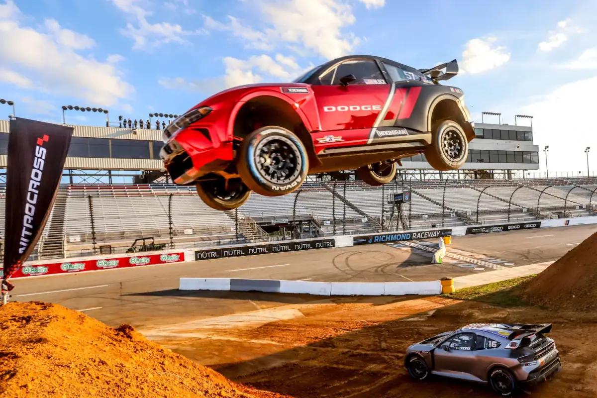 Red Dodge Nitrocross off-road rally car mid-air jump at Richmond Raceway during competition