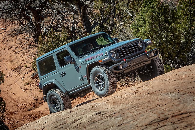 2025 Gray Jeep Wrangler Rubicon climbing a rocky off-road trail surrounded by desert brush