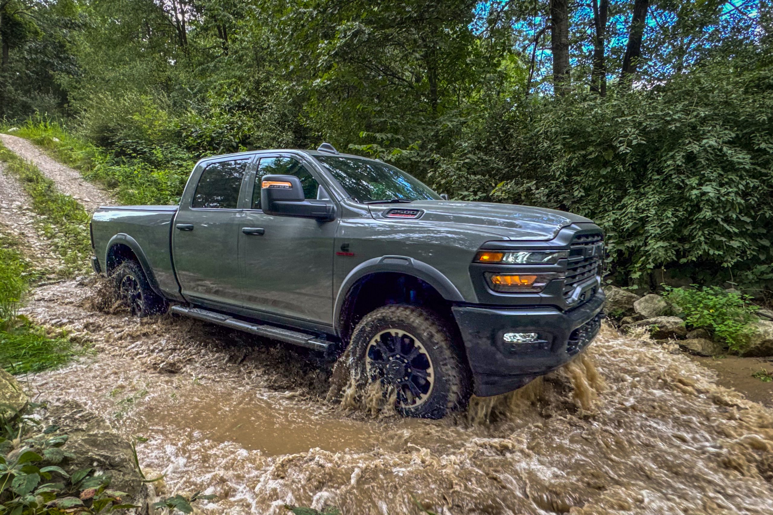 2026 Gray Ram 2500 pickup truck fording a flooded forest trail, showcasing off-road capability